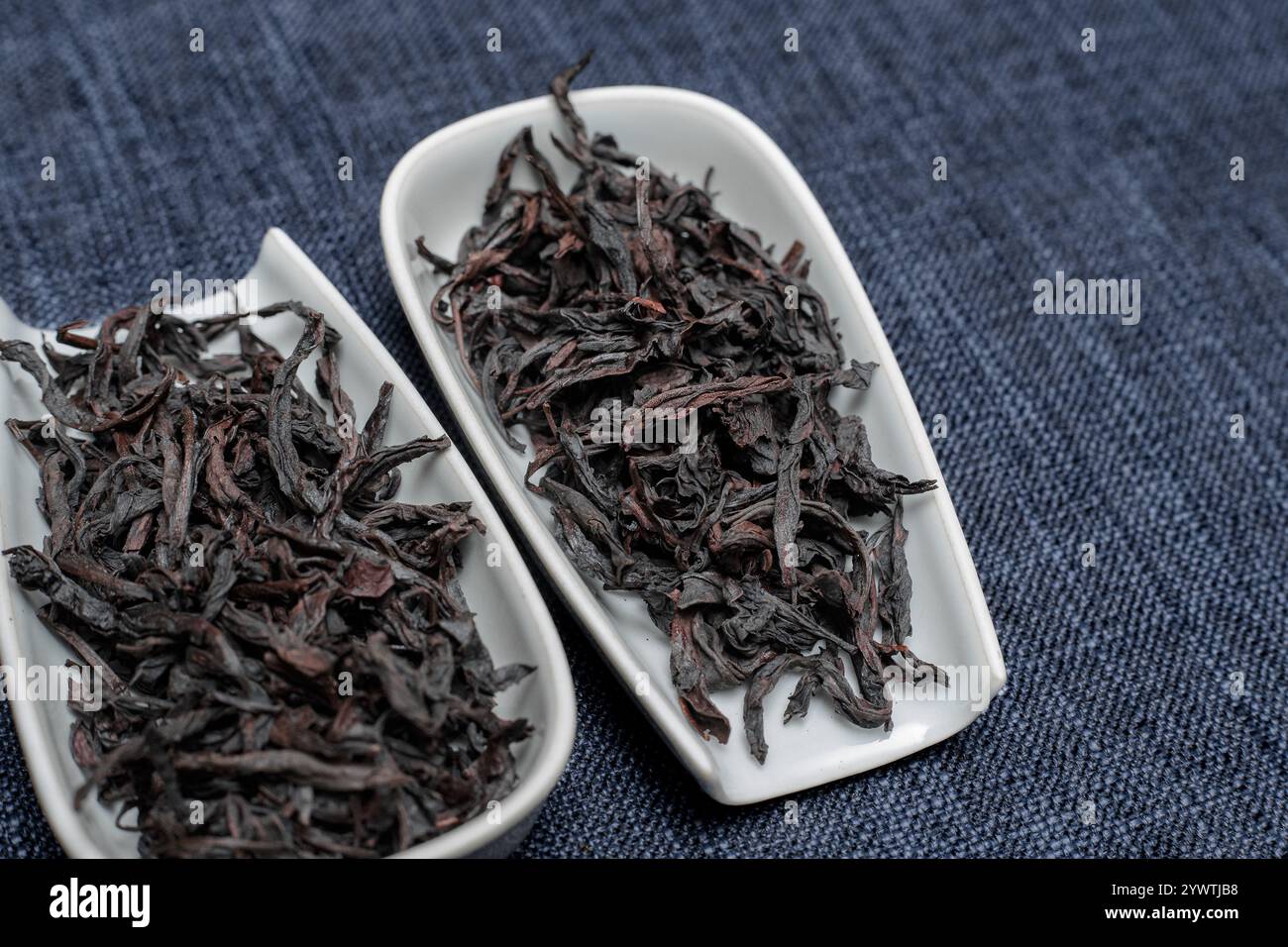 Foglie di tè nero eleganti e di alta qualità splendidamente esposte in eleganti e raffinati piatti bianchi Foto Stock