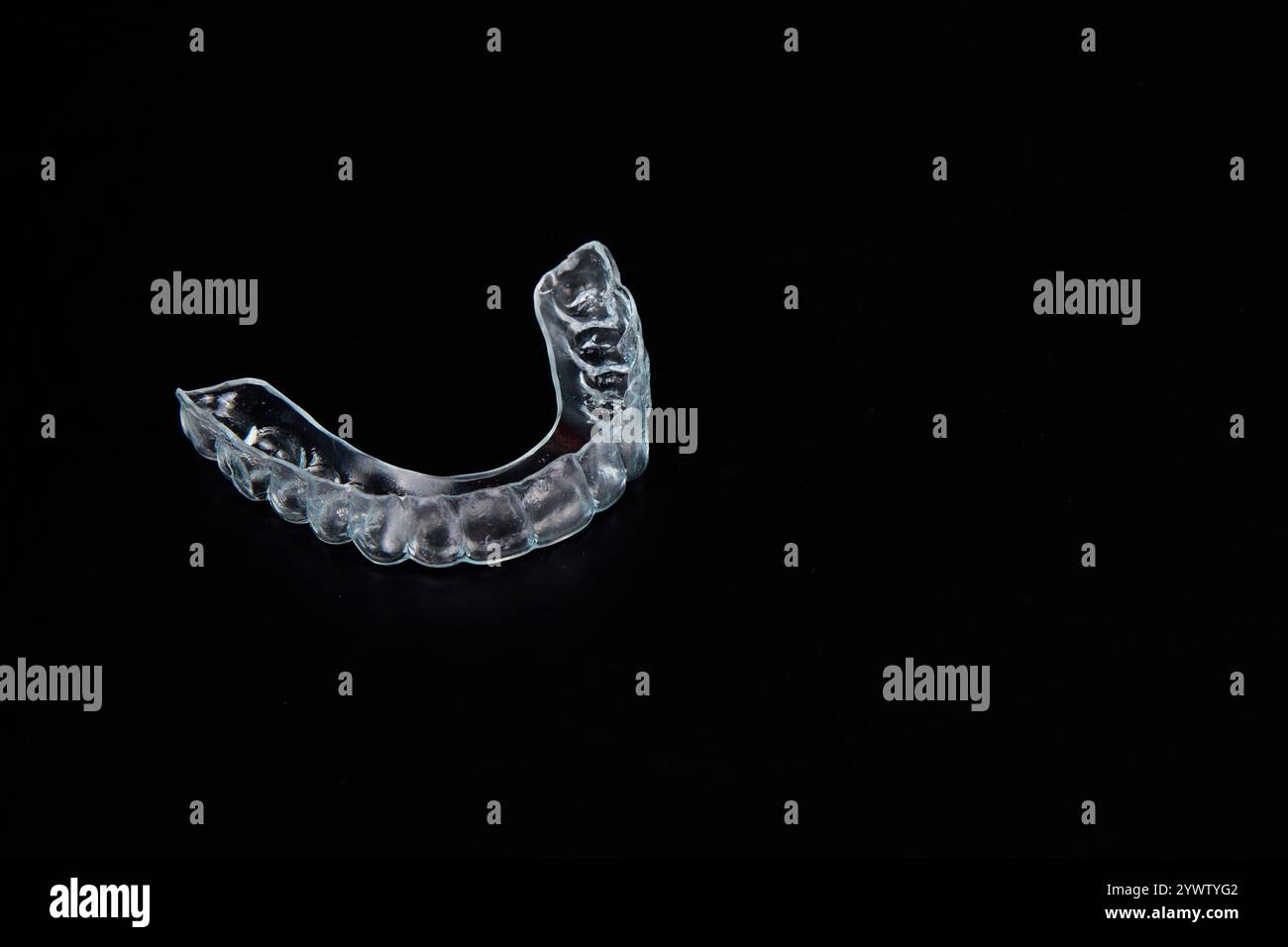 Una protezione per la bocca trasparente si appoggia su un'elegante superficie nera, simboleggiando elementi quali protezione, stile e innovazione del design Foto Stock