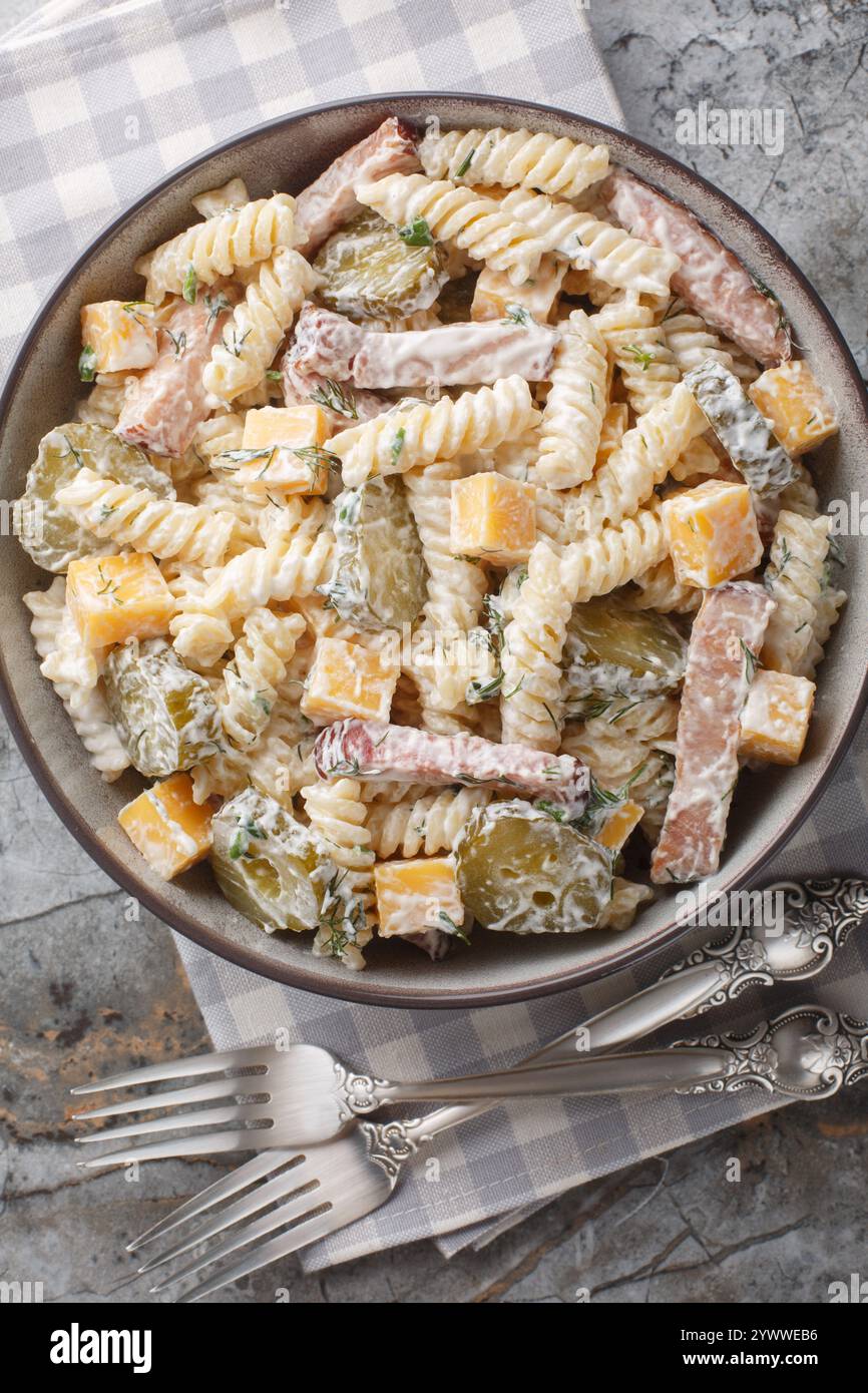 Fusilli con condimento cremoso, sottaceti, pancetta e formaggio cheddar da vicino in una ciotola sul tavolo. Vista dall'alto verticale Foto Stock