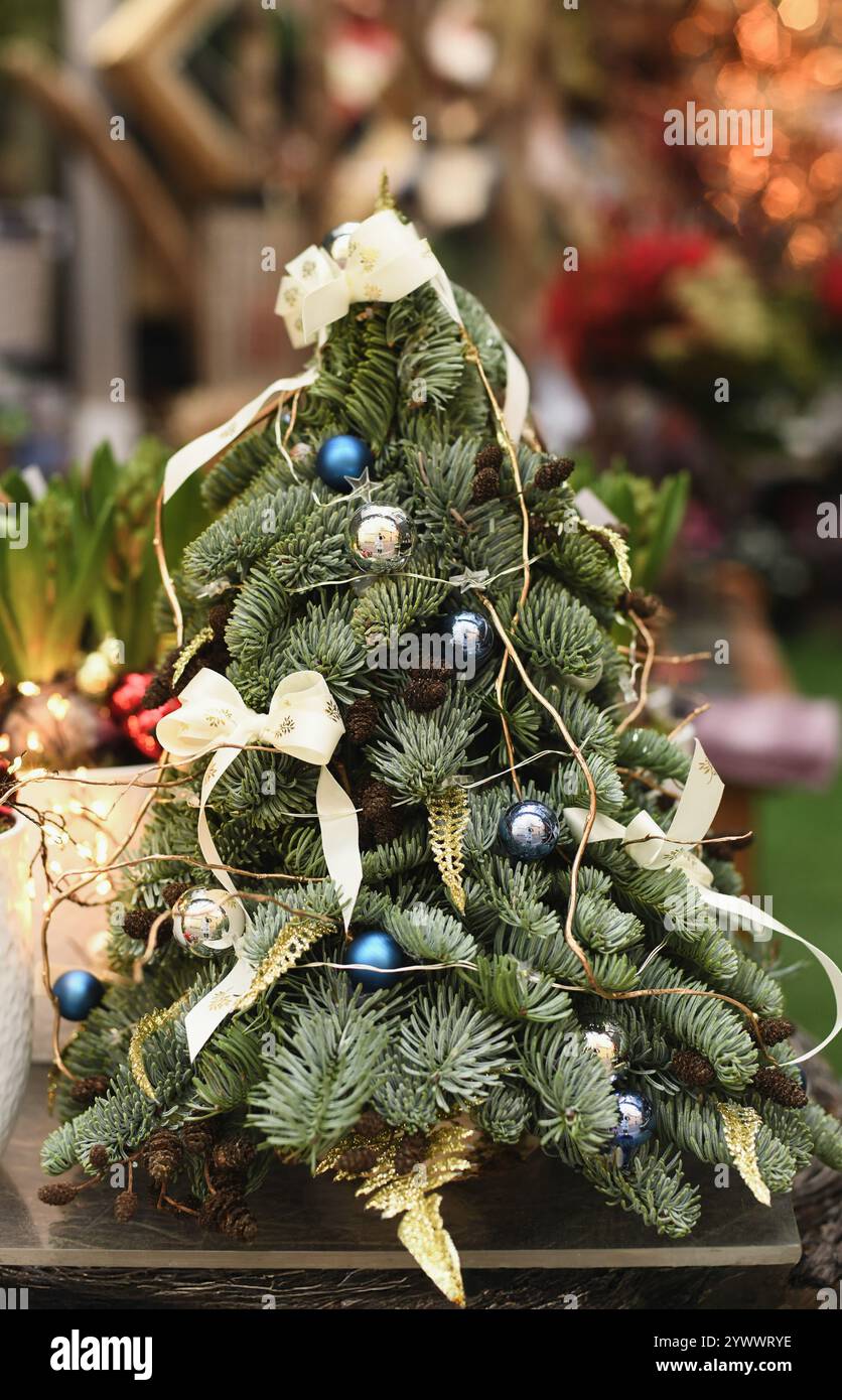 Albero di Natale in miniatura decorato con coni, archi e palle Foto Stock