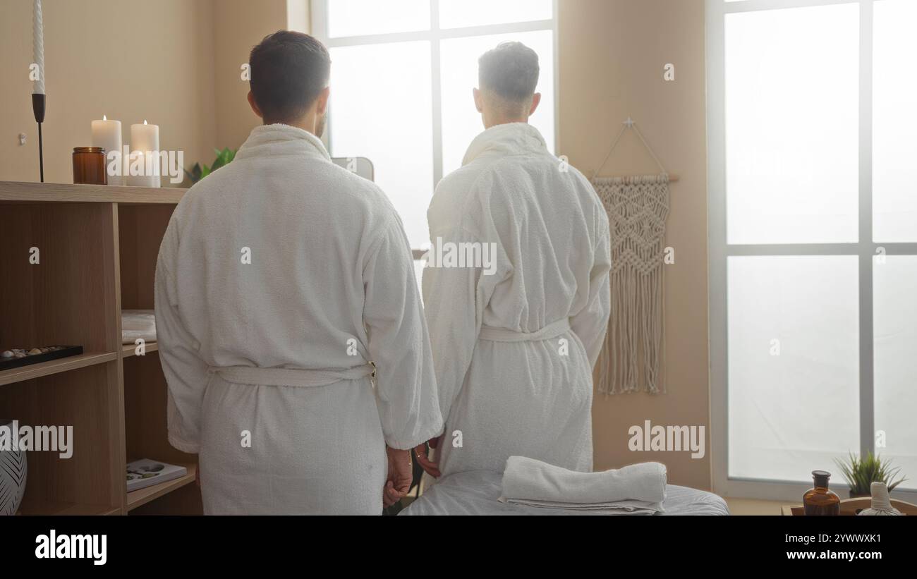 Due uomini in abiti bianchi si uniscono in una tranquilla sala spa, simboleggiando l'amore gay e la famiglia all'interno di un centro benessere. Foto Stock