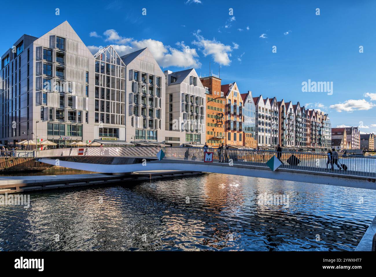 Skyline della città di Danzica in Polonia. Granary Island con una fila di edifici ristrutturati e un ponte sospeso sul fiume Motlawa. Foto Stock