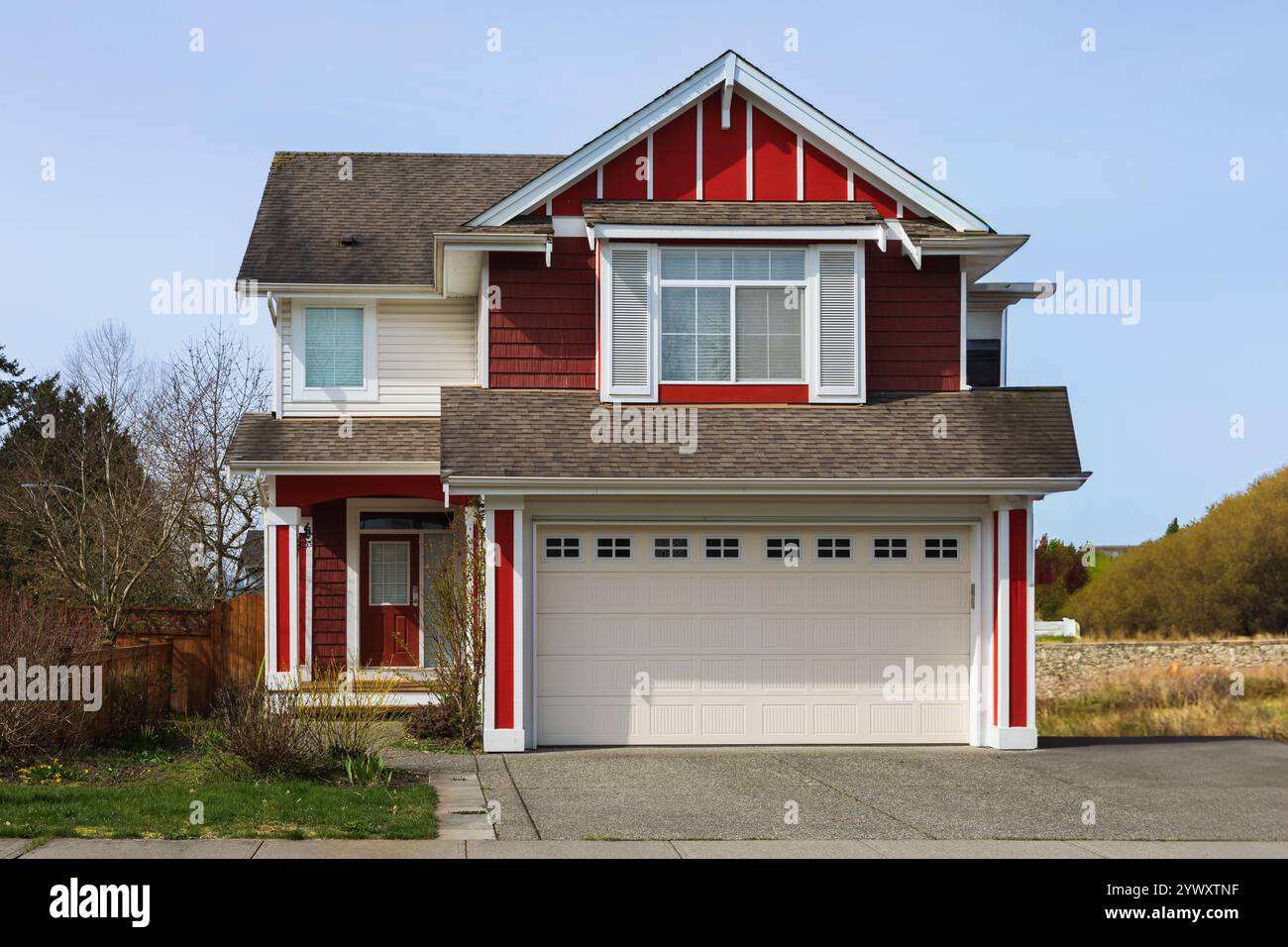 Casa di fronte all'esterno del Real Estate in una giornata di sole. Casa di lusso su misura con vialetto di accesso al garage in periferia. Casa dal design moderno Foto Stock