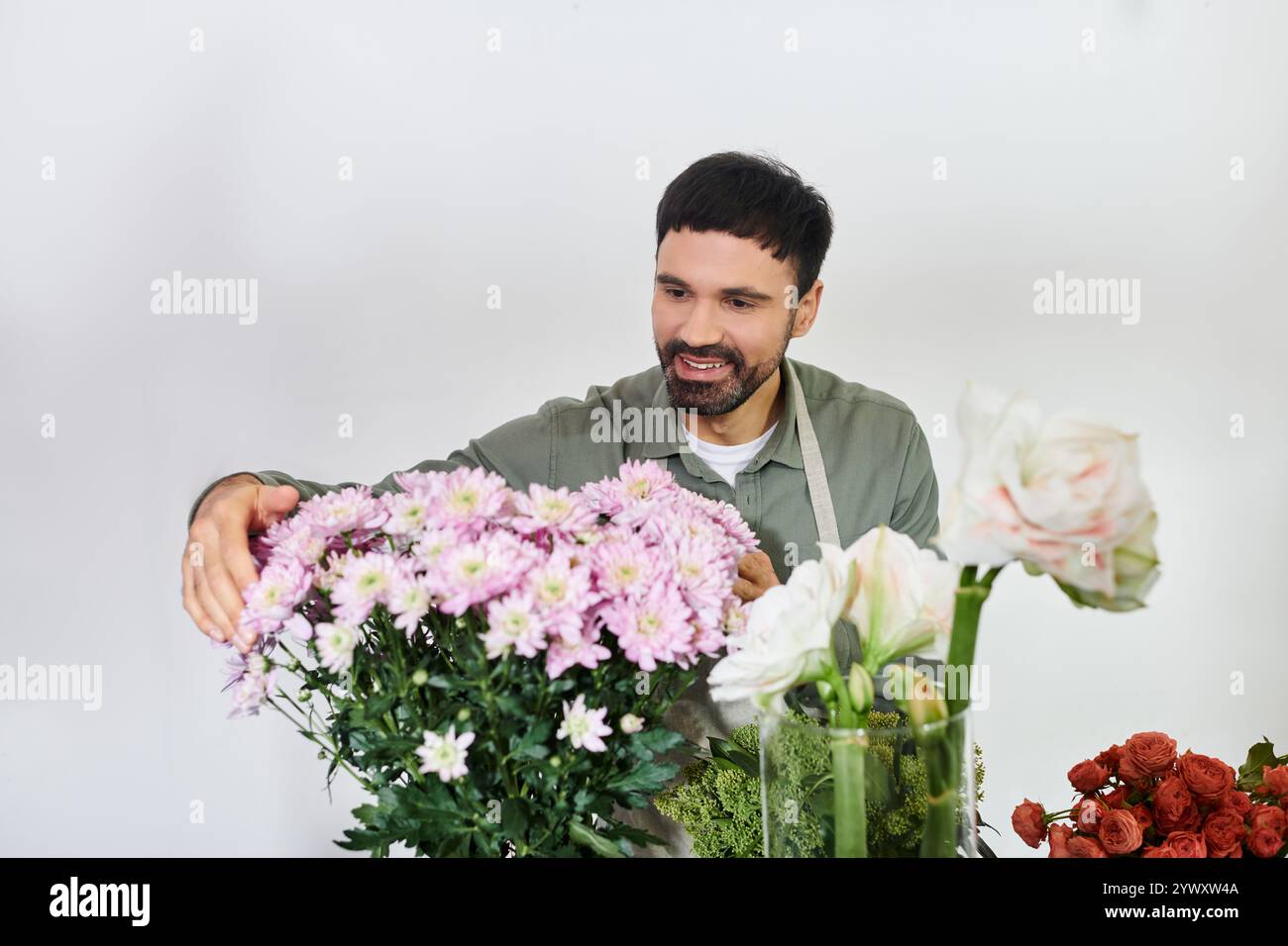 Un uomo barbuto organizza maestosamente fiori mozzafiato nel suo negozio, mostrando il suo amore per la floristeria. Foto Stock