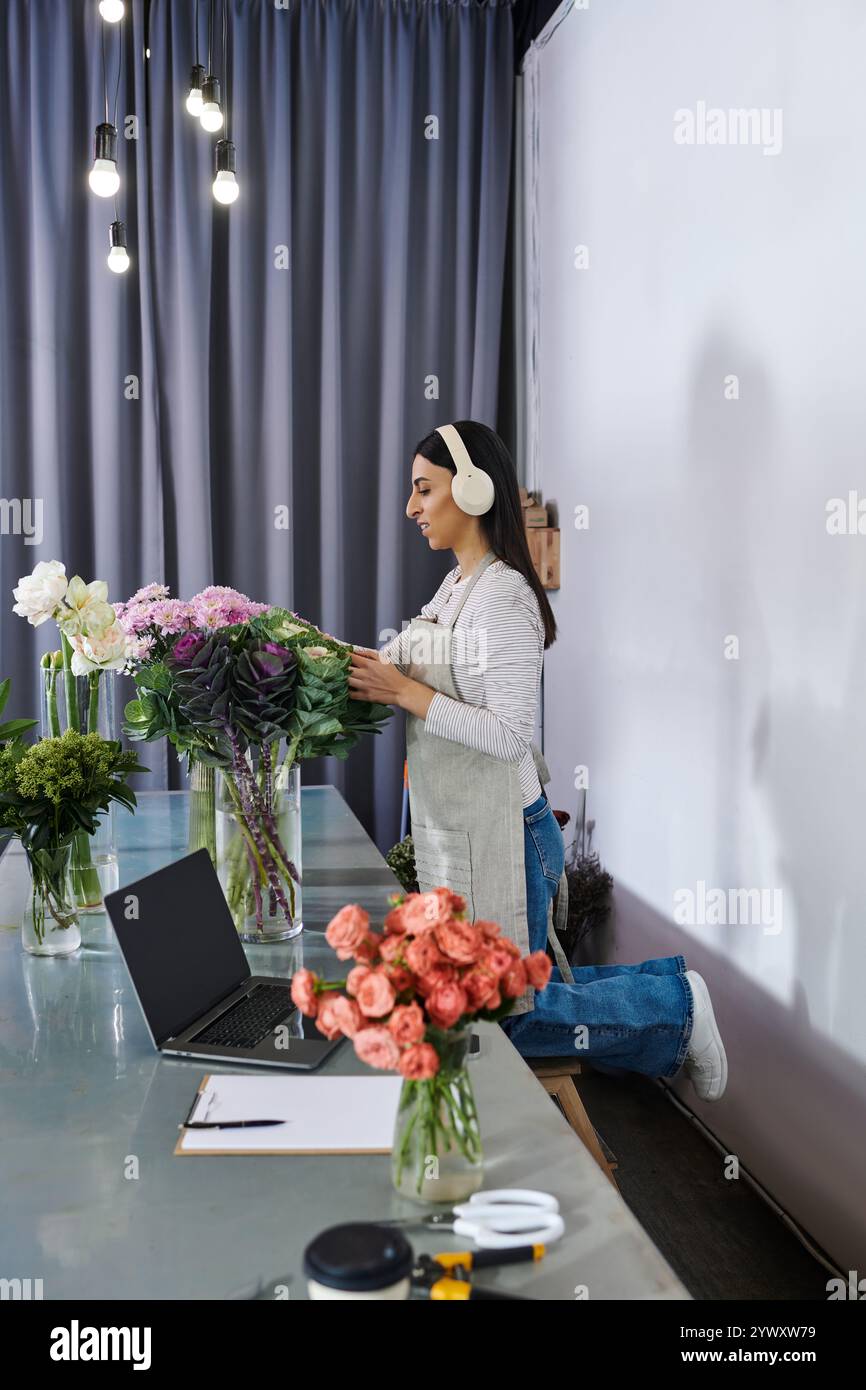 Una fiorista creativa organizza fioriture vivaci mentre gestisce le sue piccole attività aziendali. Foto Stock