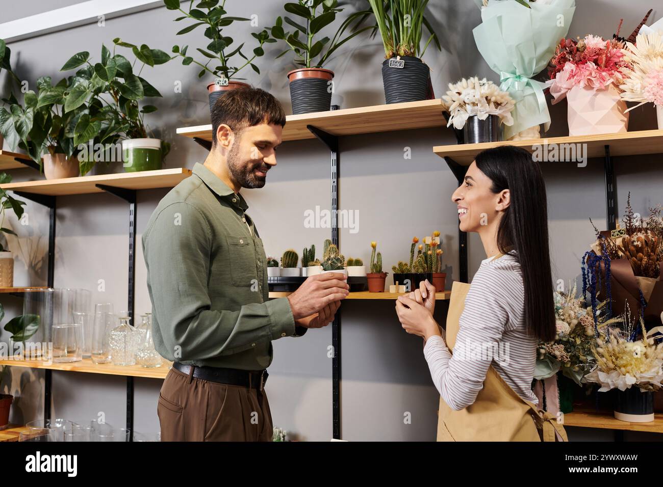 Un fiorista si impegna con un cliente maschile, condividendo competenze su piante e fiori bellissimi. Foto Stock