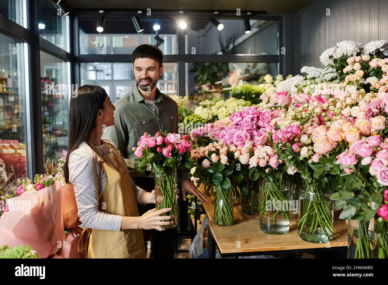 Un fiorista dedicato sta aiutando un cliente maschio a scegliere splendidi fiori nel suo affascinante negozio. Foto Stock
