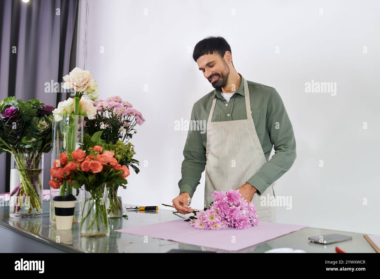 Un bell'uomo barbuto organizza un bouquet nel suo negozio di fiori, mostrando la sua creatività e passione. Foto Stock