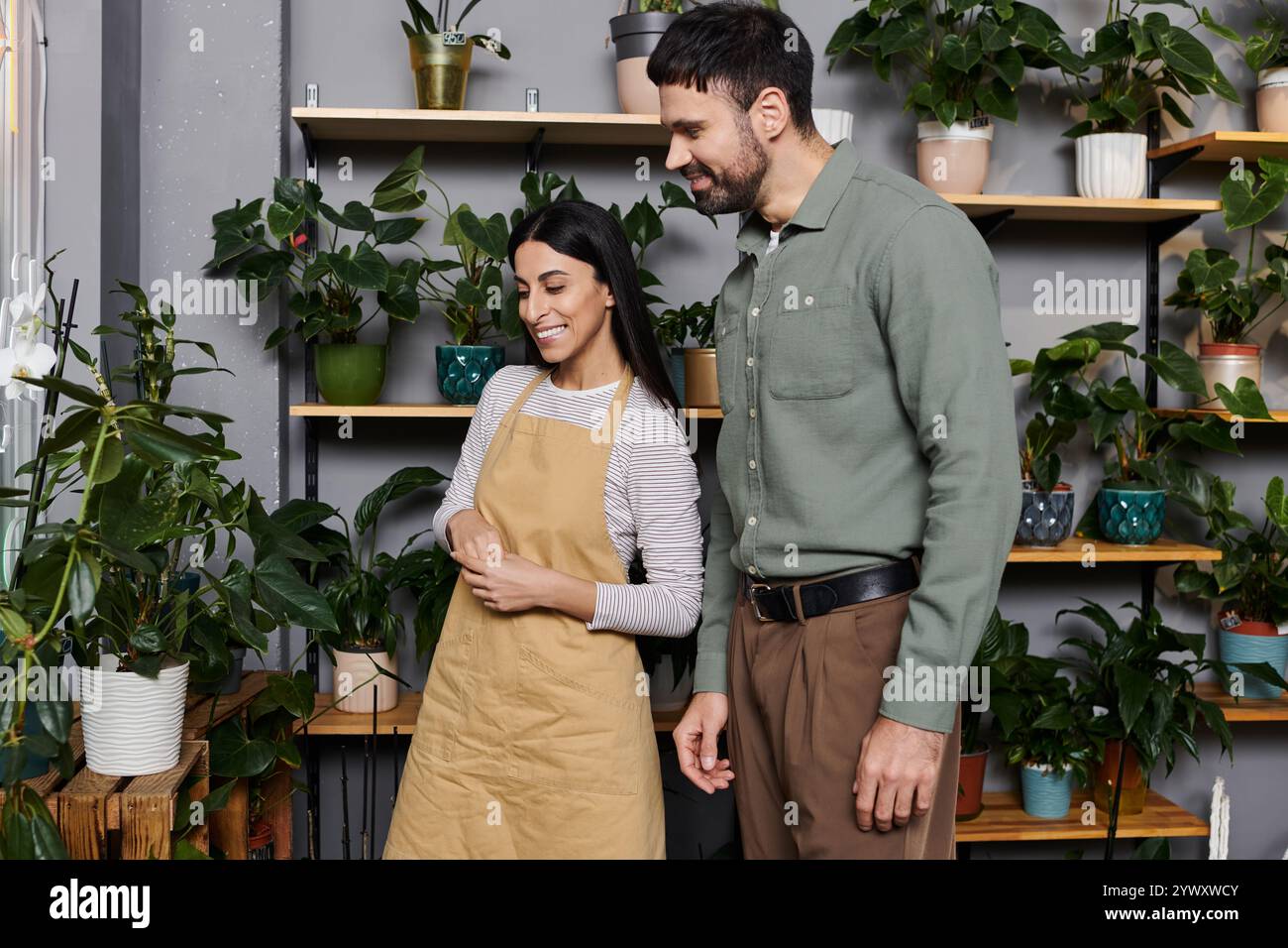 Un fiorista esperto assiste un cliente nella selezione di splendide piante nel suo negozio. Foto Stock