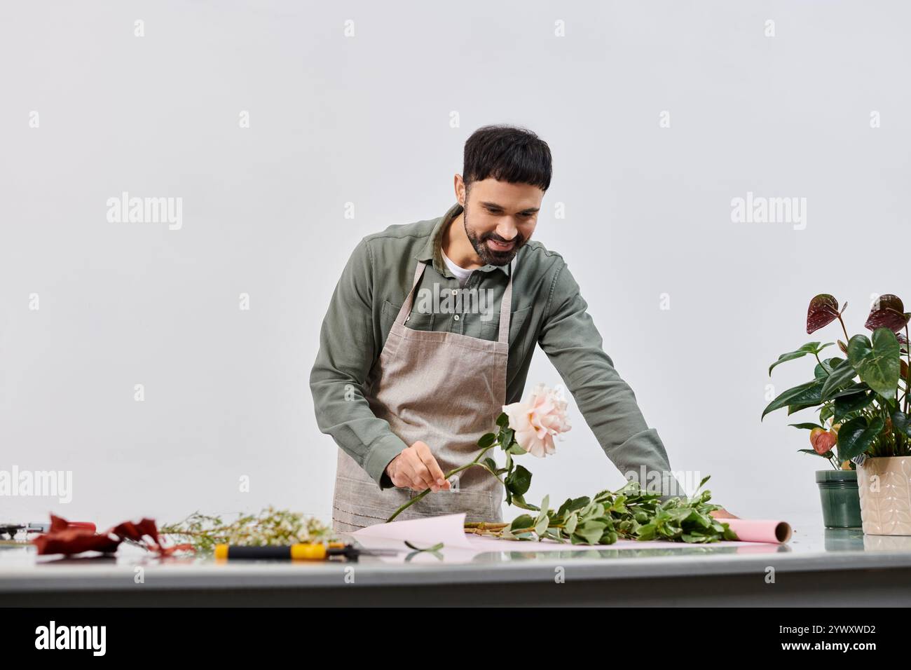 Un bell'uomo barbuto crea una bella disposizione floreale nel suo negozio. Foto Stock