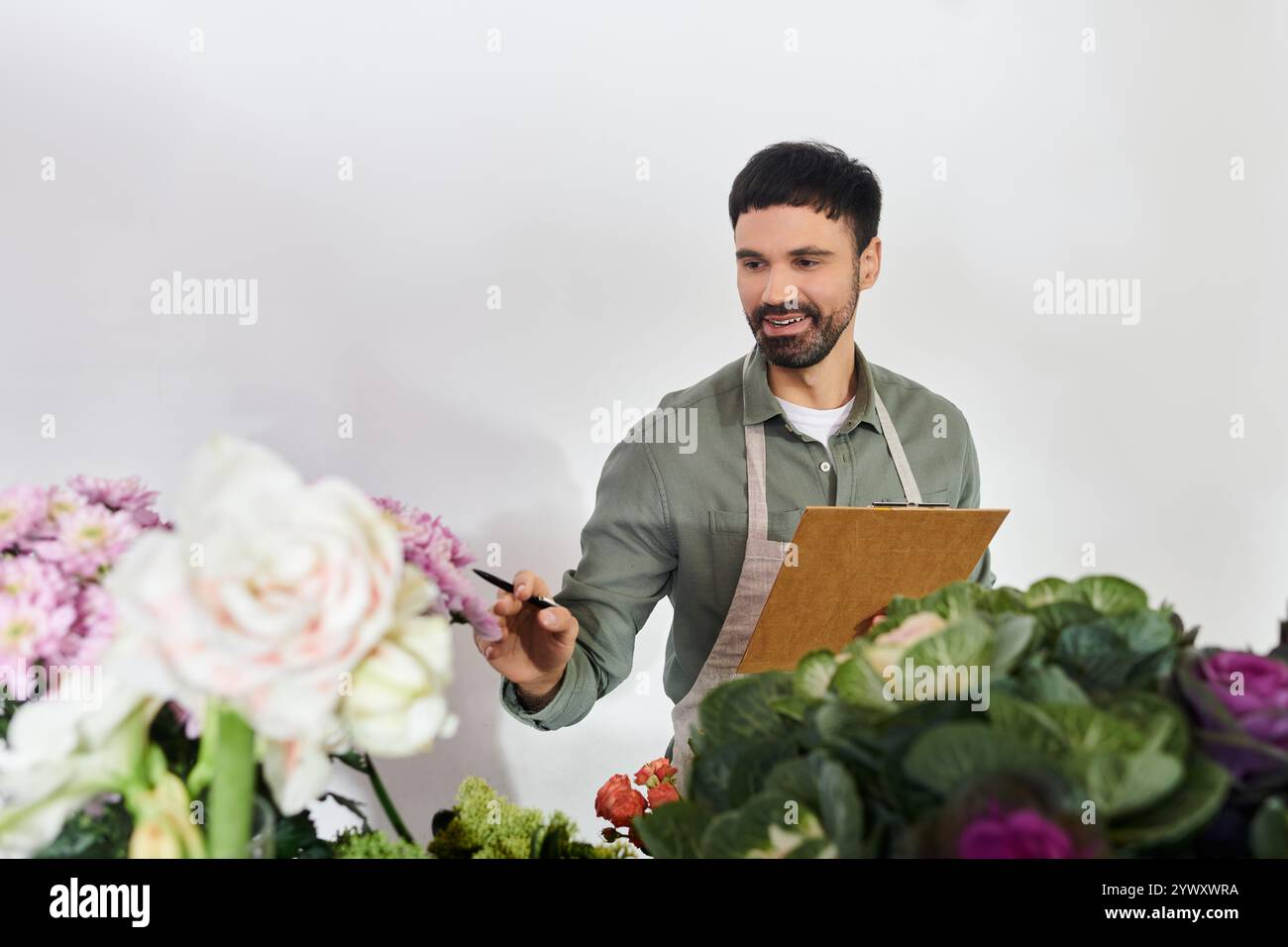Un fiorista esperto seleziona con cura i fiori mentre crea composizioni straordinarie nel suo negozio. Foto Stock