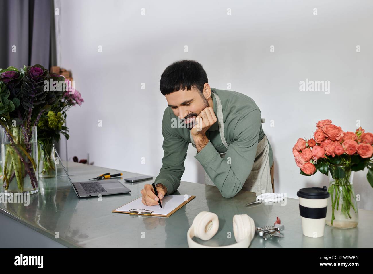 Un fiorista esperto realizza con cura composizioni floreali mentre si gode il suo ambiente accogliente. Foto Stock