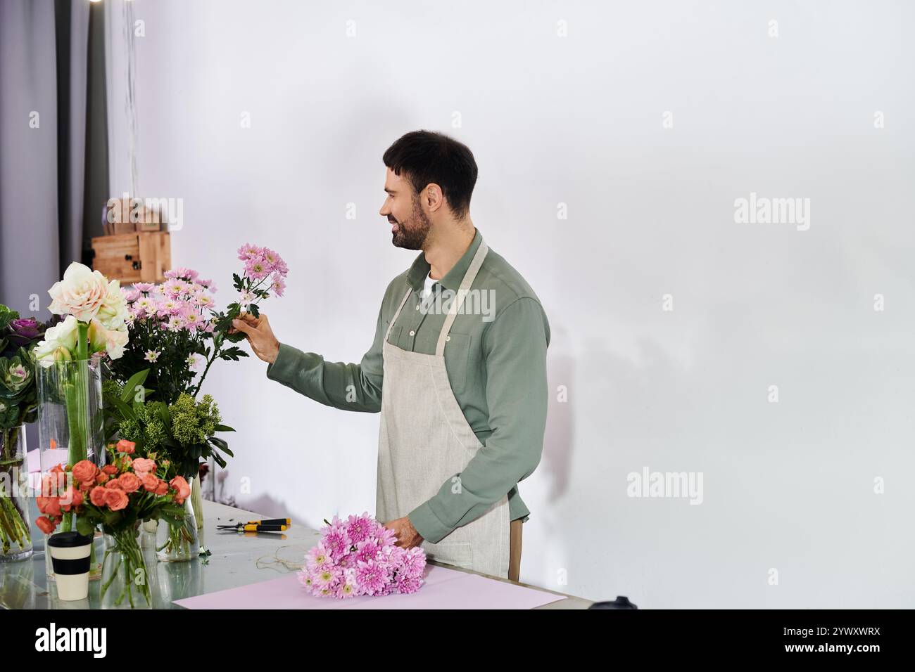 Un fiorista esperto seleziona con cura fiori vivaci per creare composizioni straordinarie nel suo negozio. Foto Stock