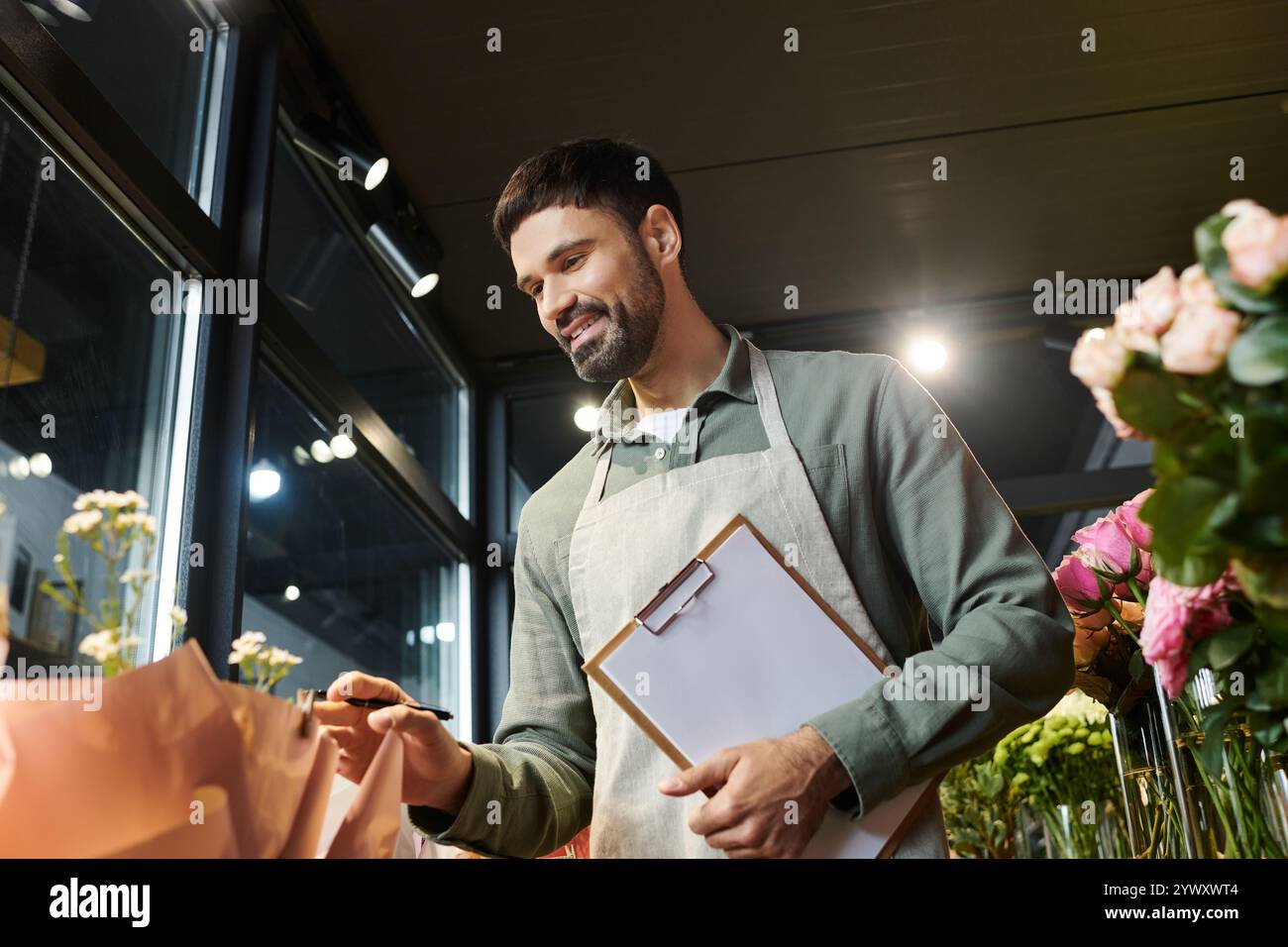Un abile uomo barbuto cura splendidi fiori nel suo vivace negozio, mostrando il suo talento. Foto Stock