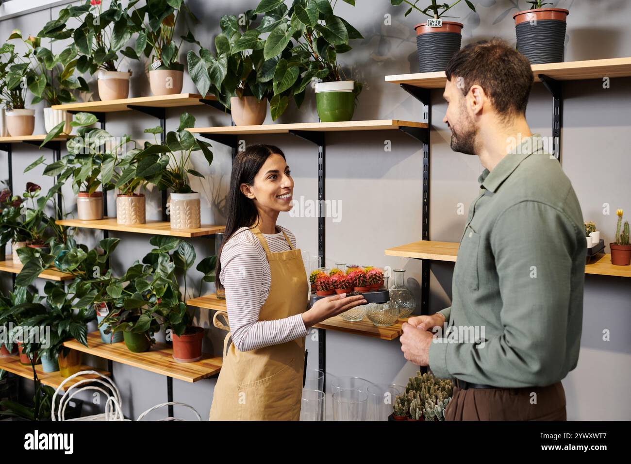 Un fiorista esperto assiste un cliente maschile, mostrando splendide piante per la selezione. Foto Stock