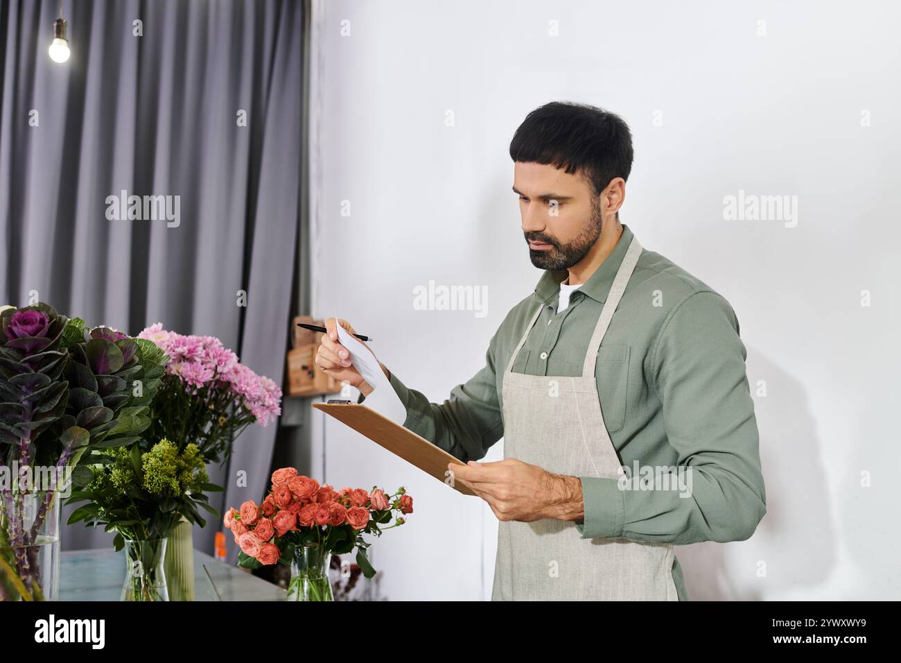 Un fiorista esperto gestisce con cura gli ordini mentre è circondato da fiori colorati e vegetazione. Foto Stock
