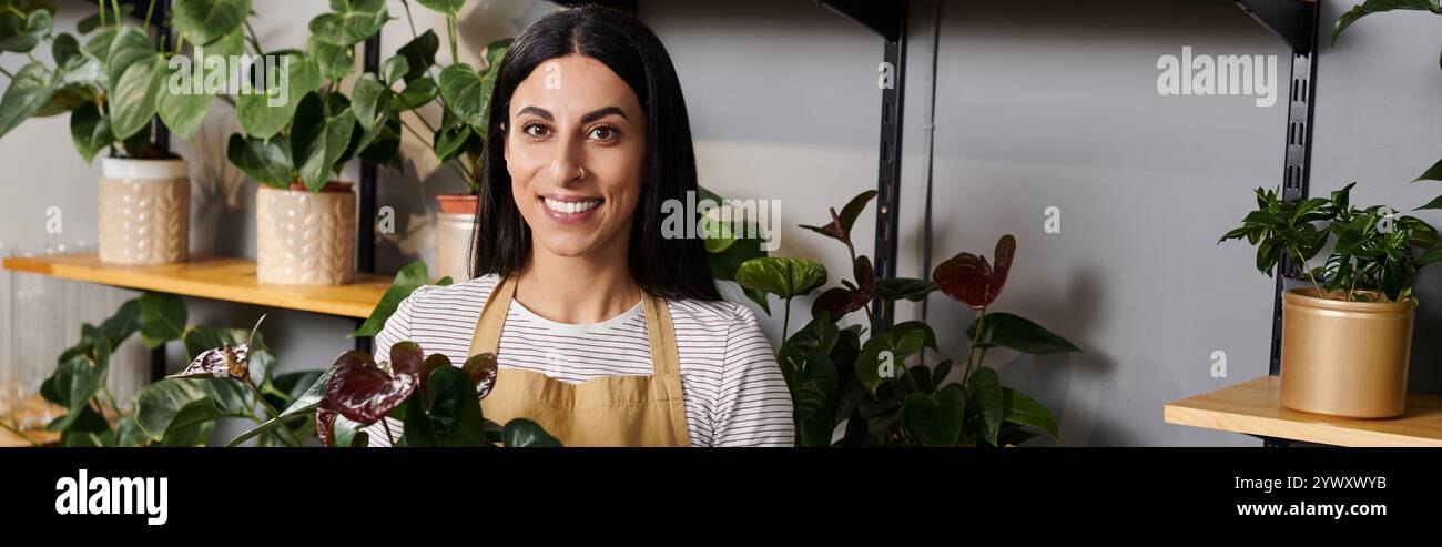 Un fiorista esperto organizza con sapienza splendide piante mentre sorride nel suo accogliente negozio. Foto Stock