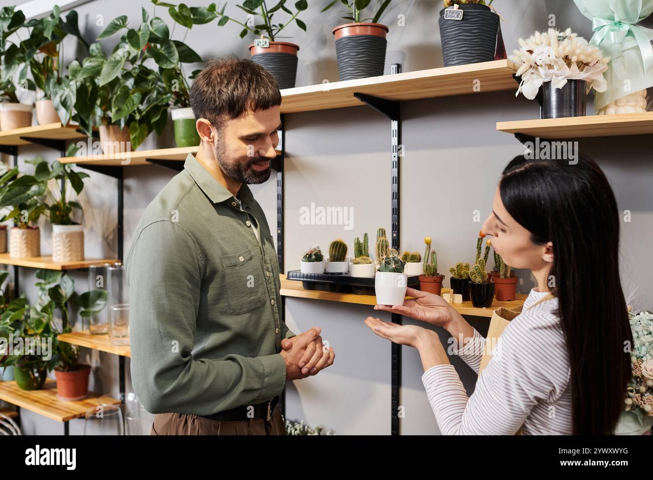 Un fiorista esperto si consulta con un cliente maschile, condividendo informazioni sulle piante in vaso. Foto Stock