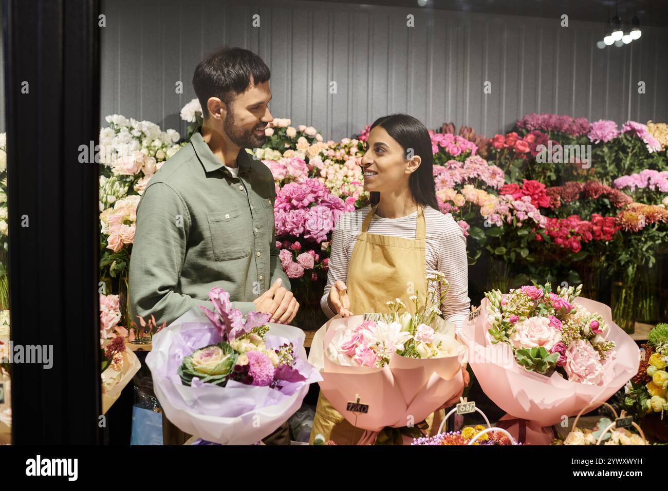 Un fiorista esperto si impegna con un cliente maschile, mostrando vivaci disegni floreali e arrangiamenti. Foto Stock
