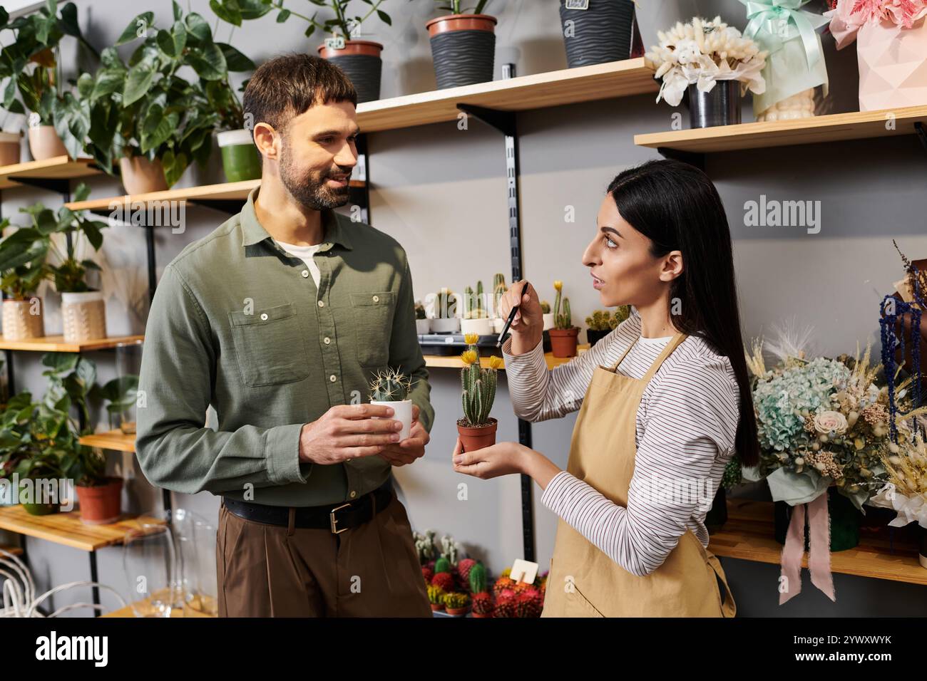 Un fiorista esperto coinvolge un cliente mentre espone una varietà di piante e fiori. Foto Stock