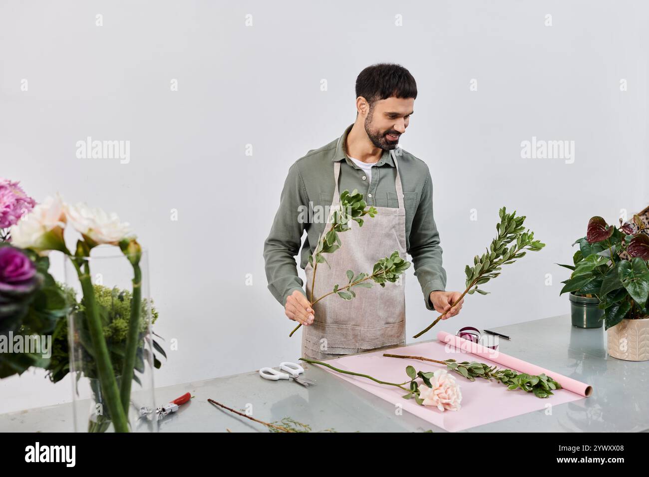 Un fiorista esperto crea bellissime esposizioni nel suo invitante negozio, immerso nel verde lussureggiante. Foto Stock