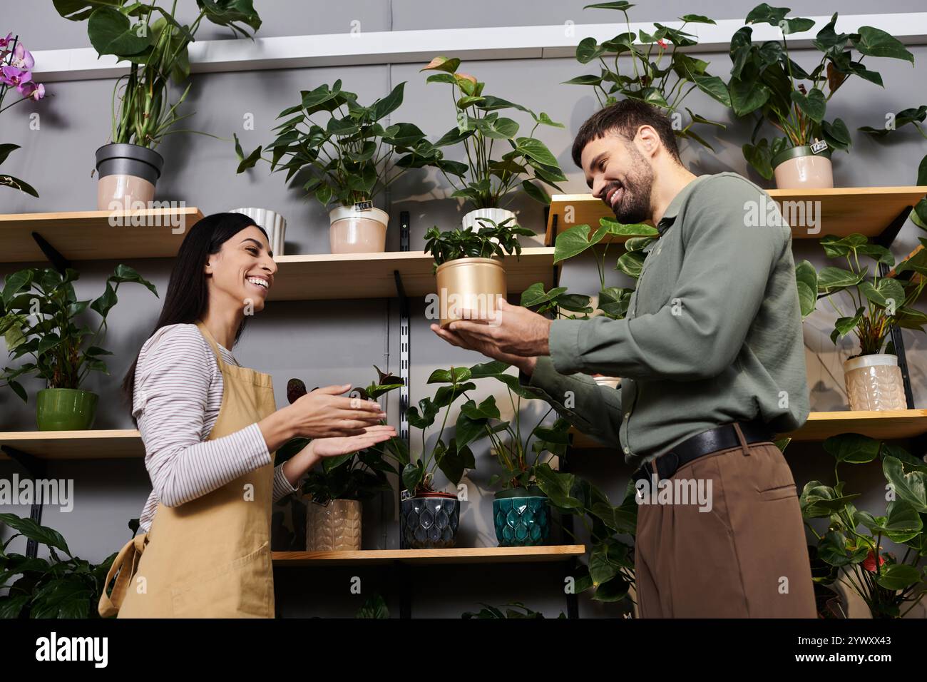 Un fiorista esperto condivide la sua passione con un cliente mentre è circondato da una vegetazione lussureggiante. Foto Stock