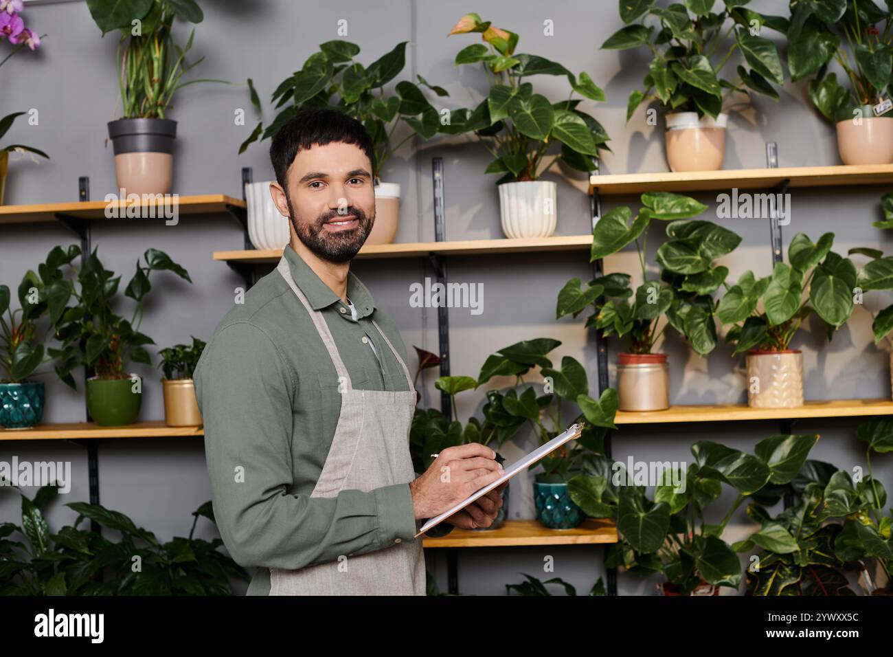 Un fiorista esperto che tende a piante vibranti in un'accogliente atmosfera da negozio di fiori. Foto Stock