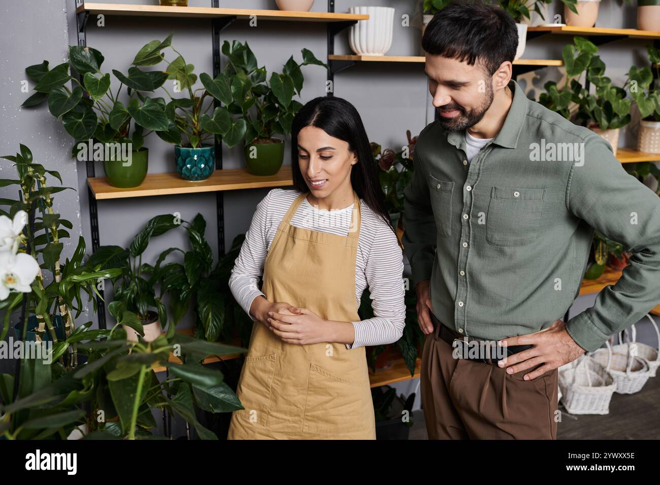 Un fiorista esperto condivide con un cliente i suoi consigli e mette in mostra piante e fiori vivaci. Foto Stock