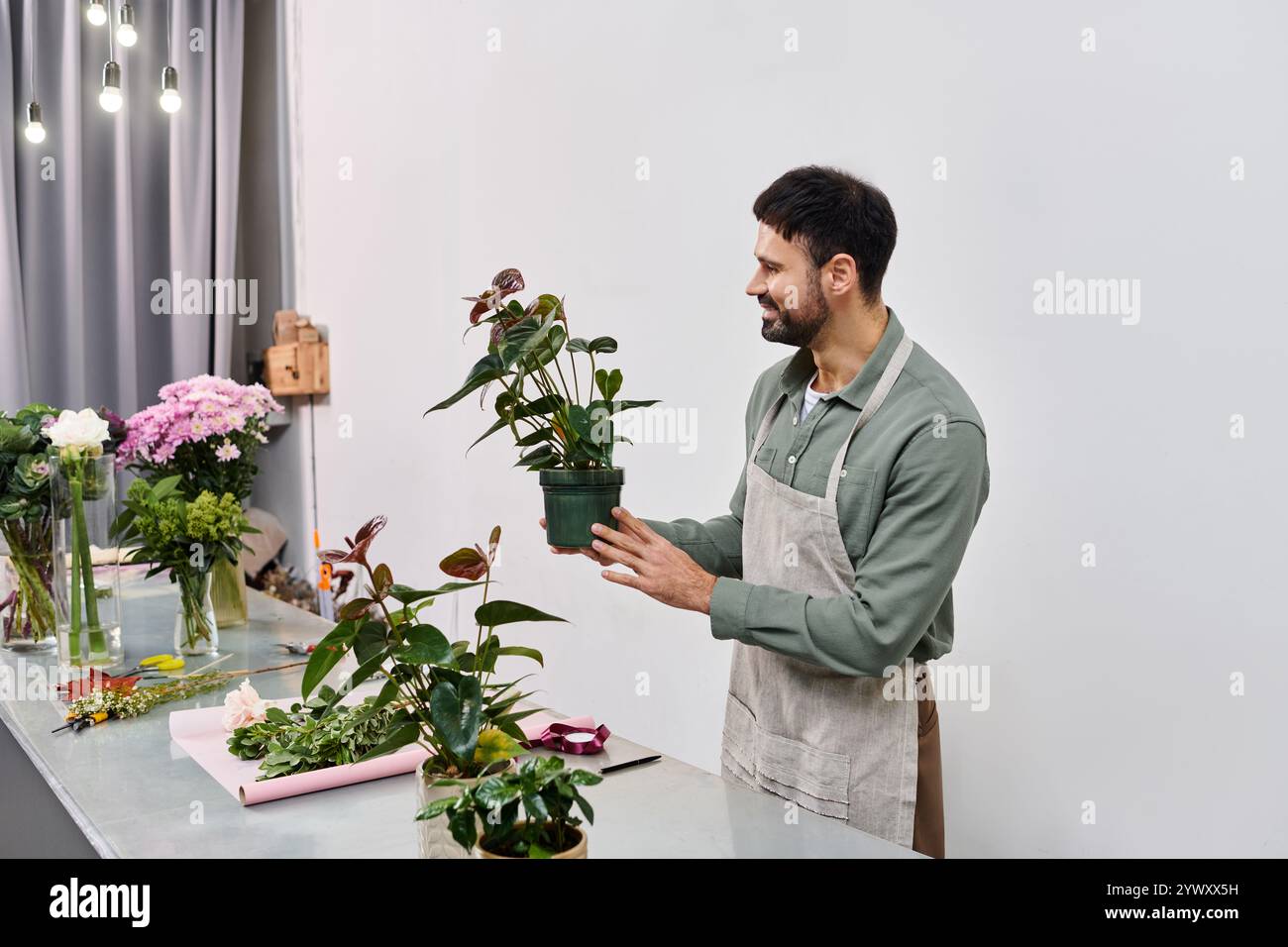 Un fiorista esperto mostra con amore piante vivaci nel suo affascinante negozio pieno di fiori. Foto Stock