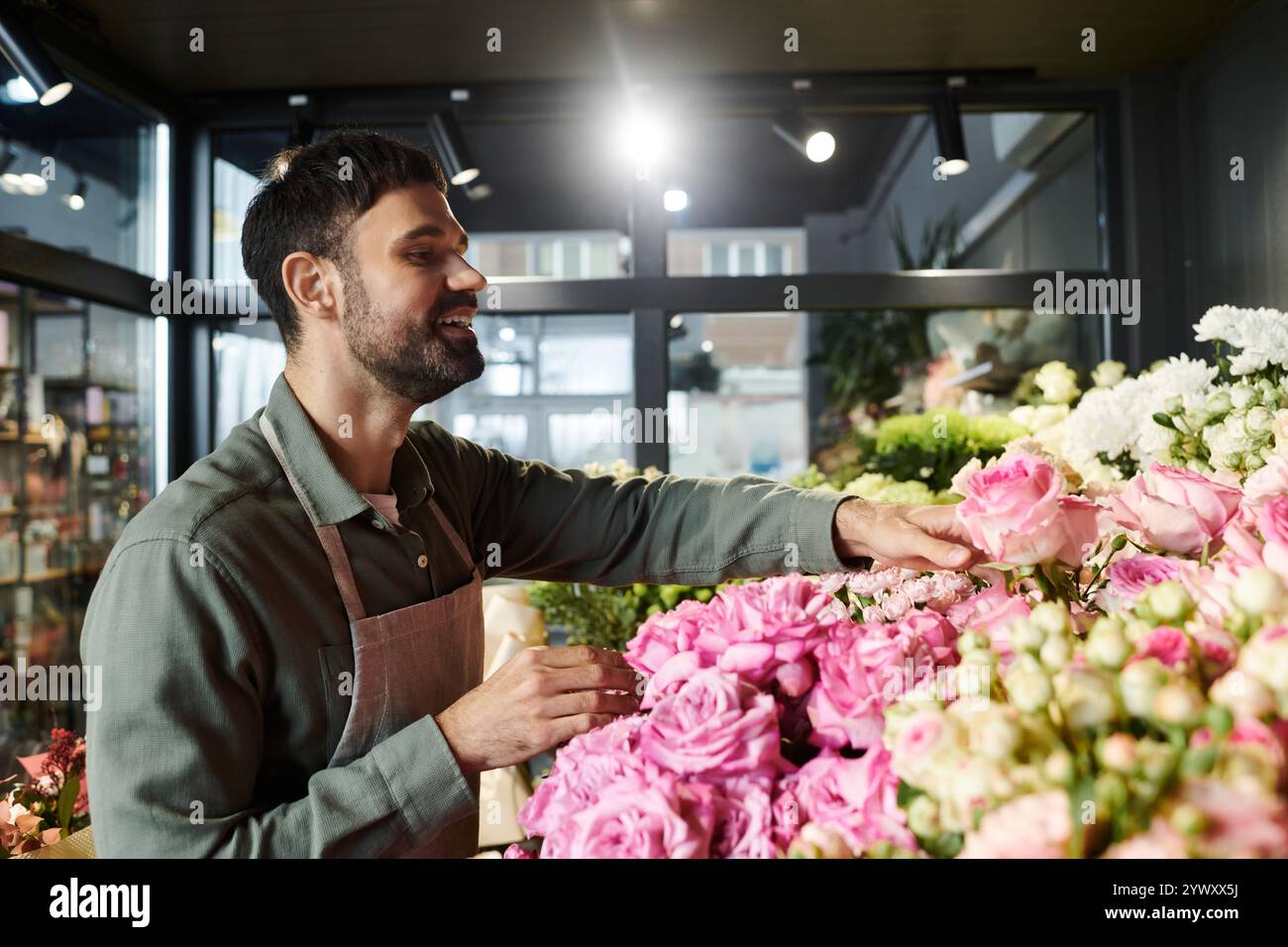 Un fiorista esperto sceglie rose mozzafiato, mostrando la sua passione e la sua arte nel negozio. Foto Stock