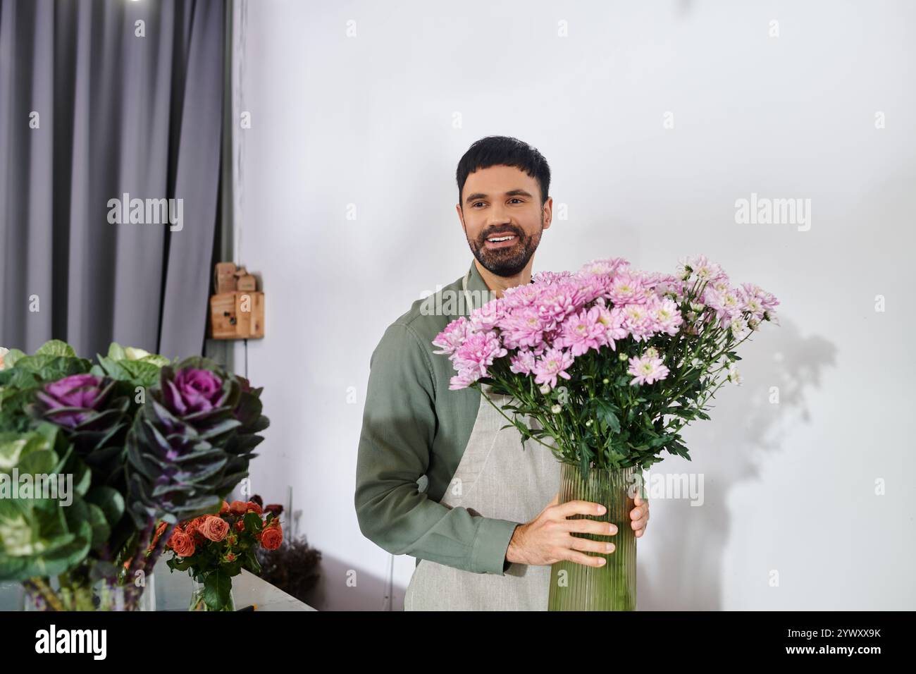 Un fiorista esperto con la barba organizza splendidi fiori in un'accogliente atmosfera da negozio. Foto Stock