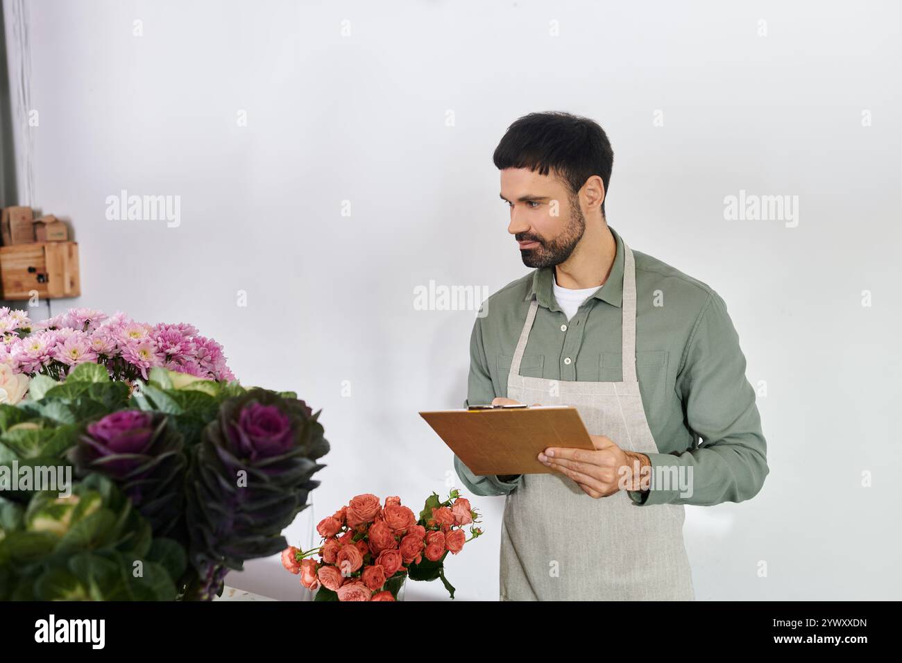 L'uomo barbuto organizza minuziosamente i fiori mentre gestisce la sua piccola impresa con cura. Foto Stock