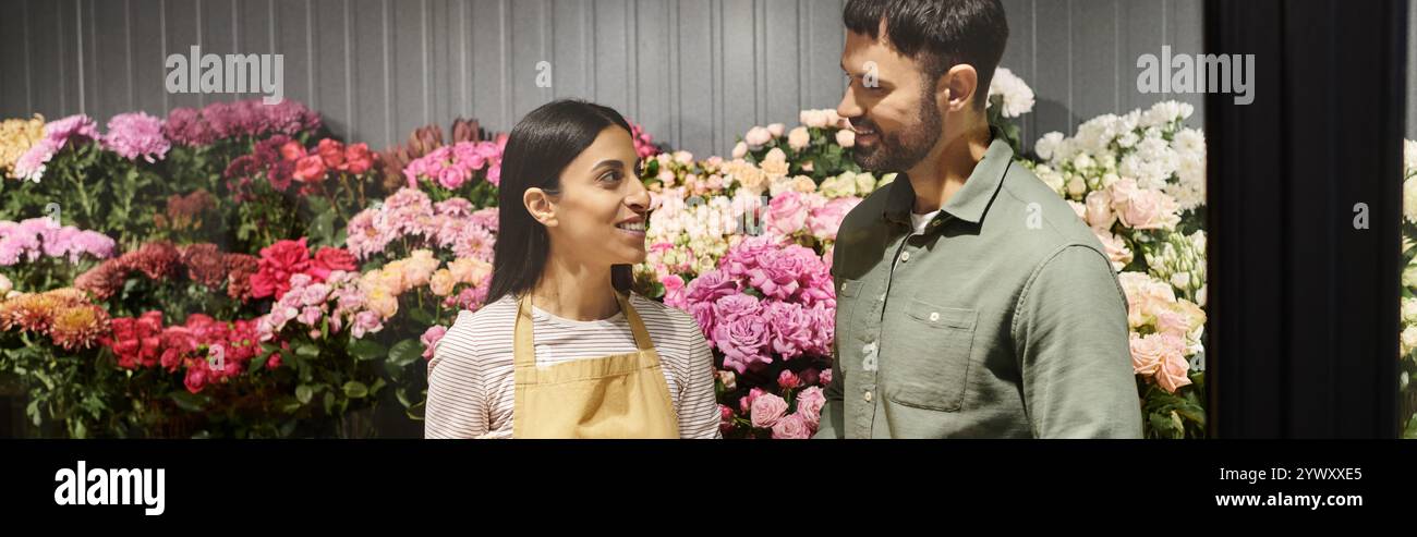 Fiori fioriti circondano un fiorista cordiale che aiuta un cliente a scegliere il bouquet perfetto. Foto Stock