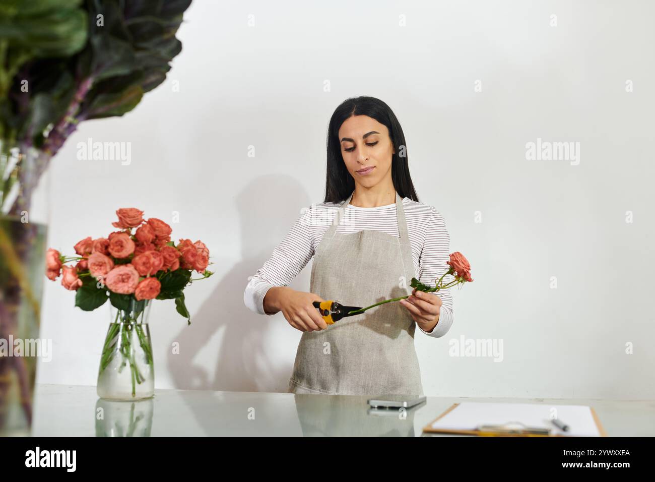 La bella fiorista bruna organizza sapientemente rose mentre gestisce la sua piccola impresa. Foto Stock
