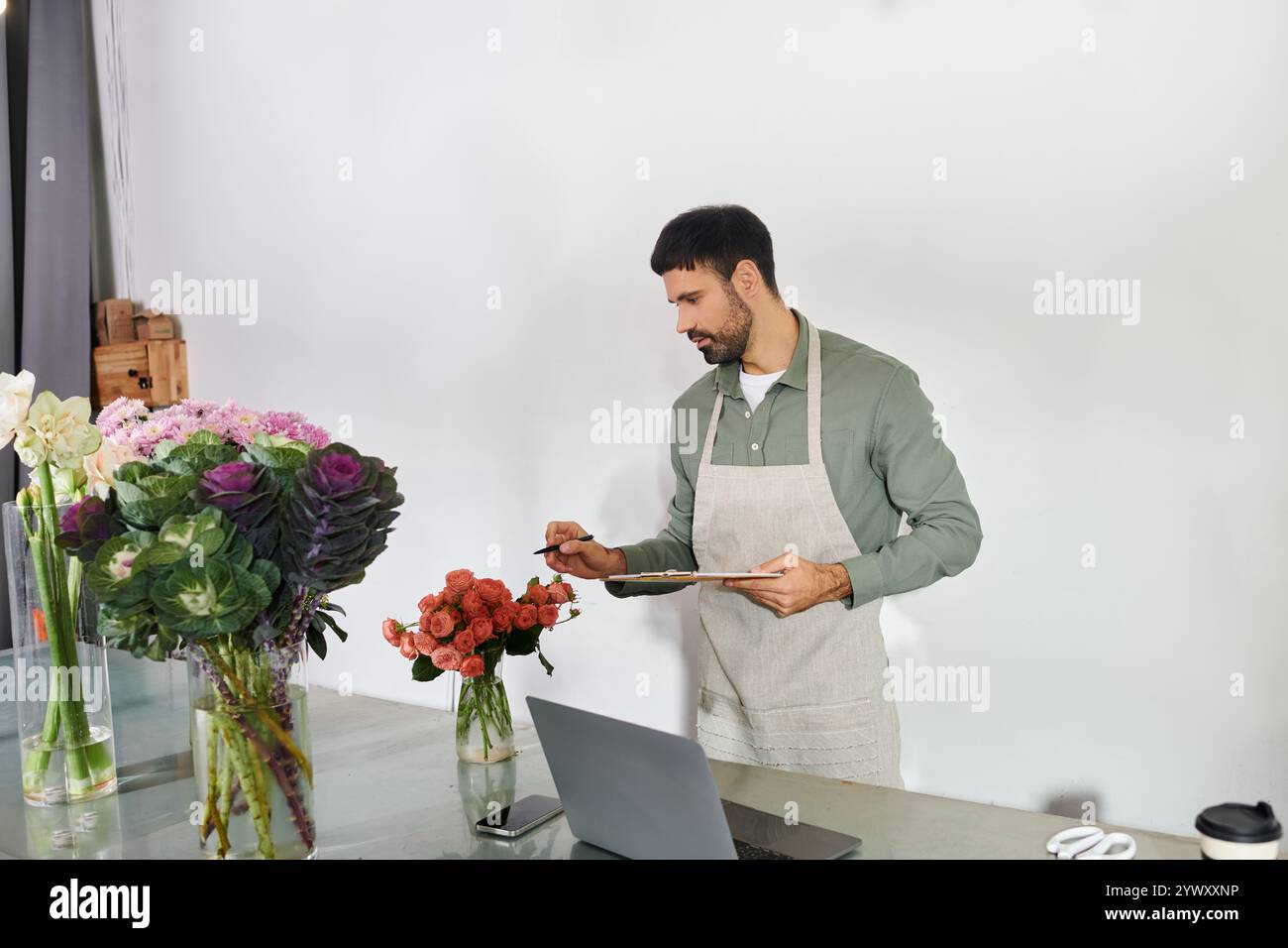Il bellissimo fioraio organizza con cura splendidi fiori nel suo negozio, mostrando il suo mestiere. Foto Stock