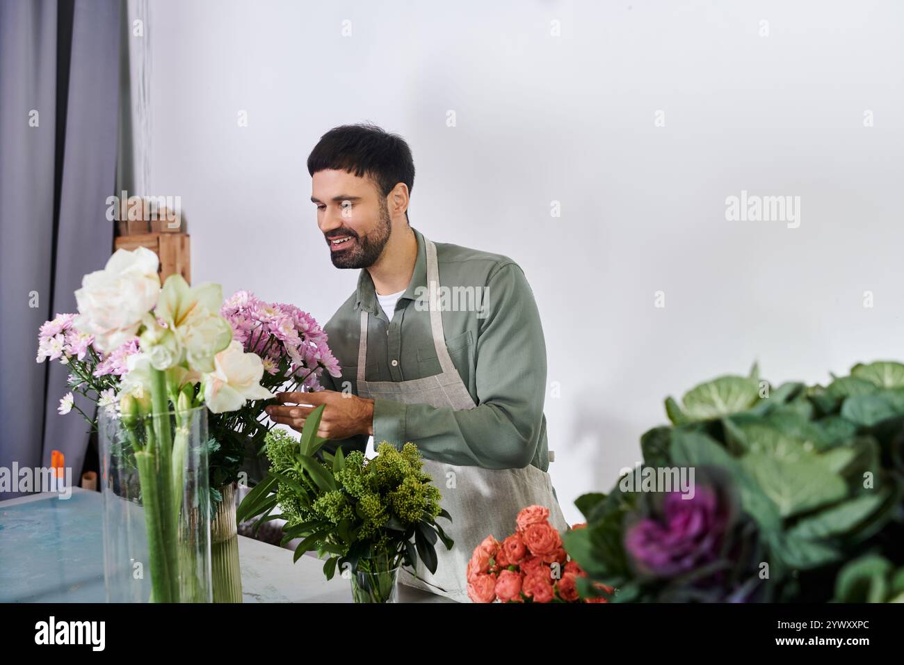 Il bell'uomo barbuto cura bellissime fioriture nel suo affascinante negozio di fiori. Foto Stock