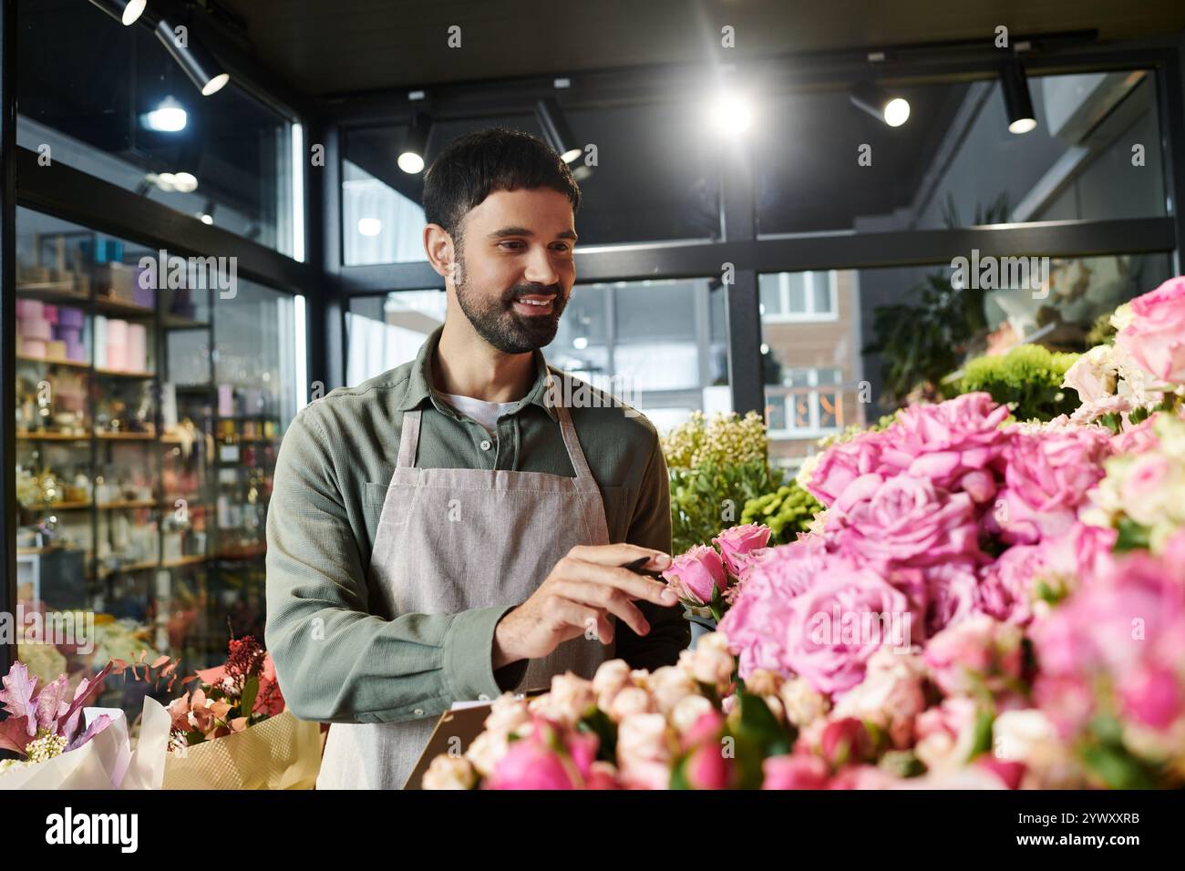 Il bell'uomo barbuto cura splendide composizioni floreali nel suo accogliente negozio. Foto Stock