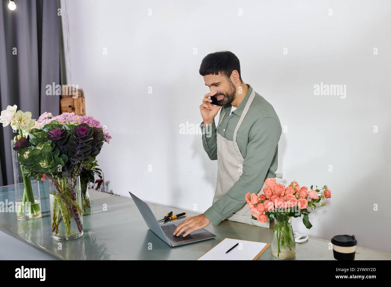 Un fiorista barbuto si impegna in affari mentre organizza splendidi fiori nel suo negozio. Foto Stock