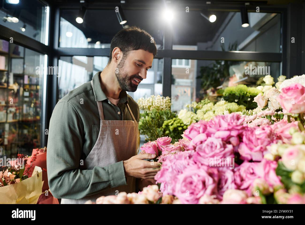 Un fiorista barbuto sceglie splendidi fiori nel suo delizioso negozio, mostrando la sua creatività e passione. Foto Stock