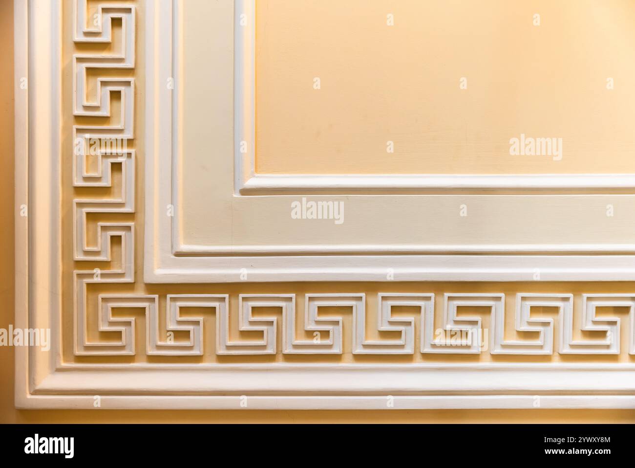 Motivo a meandro su sfondo giallo. Modanatura a parete classica, dettagli interni in stile vintage, sfondo astratto per foto architettoniche Foto Stock