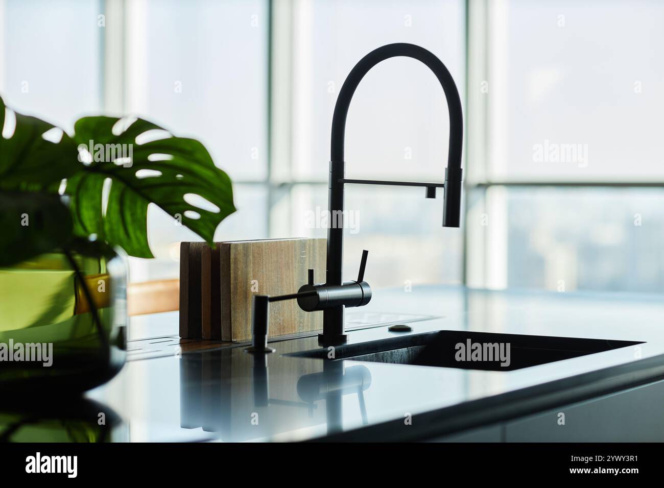 Immagine ravvicinata della silhouette del rubinetto della cucina montata su un ripiano in marmo nero in una moderna cucina minimalista, spazio fotocopie Foto Stock