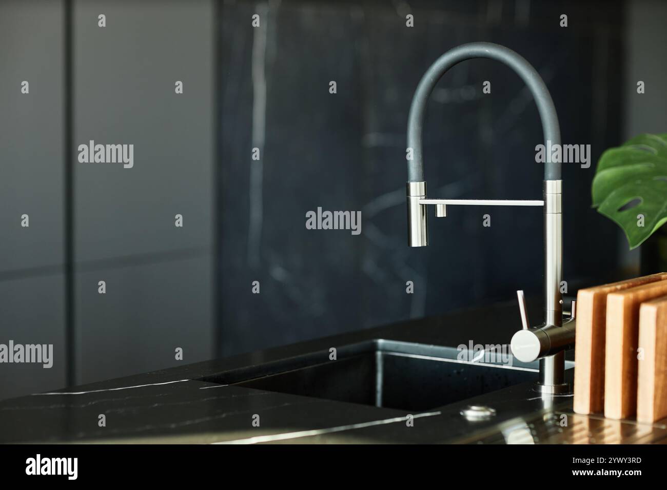 Primo piano su un moderno rubinetto da cucina cromato montato su un ripiano in marmo nero in una cucina minimalista, spazio fotocopie Foto Stock