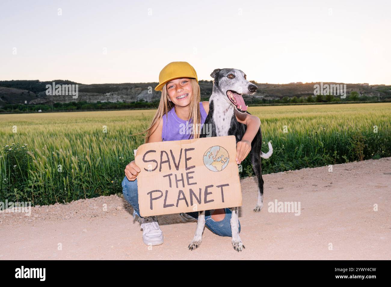 Bella adolescente con un cartello che dice di SALVARE IL PIANETA accanto al suo cane. Foto Stock