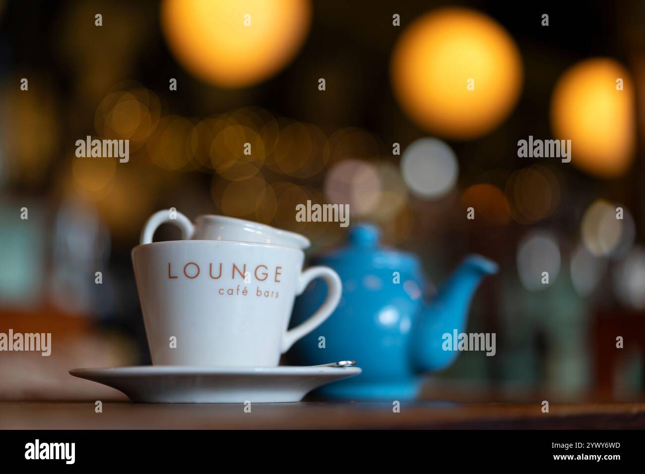 Primo piano di una teiera e di una tazza di latte sul tavolo del ristorante con una leggera illuminazione sullo sfondo. Foto Stock
