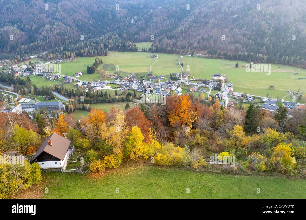 Il vivace fogliame autunnale incornicia un tranquillo villaggio annidato in una valle, la campagna slovena, la Slovenia Foto Stock