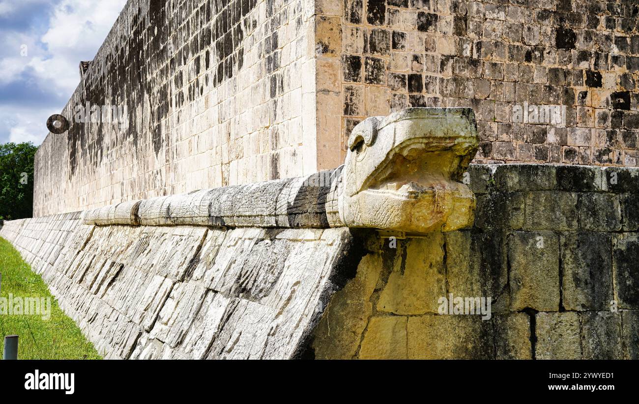 Scultura della testa del Serpente Kukulcan da vicino con vista dell'anello di pietra della parete occidentale presso il grande campo da ballo, Juego de Pelota, Chichen Itza, Messico Foto Stock
