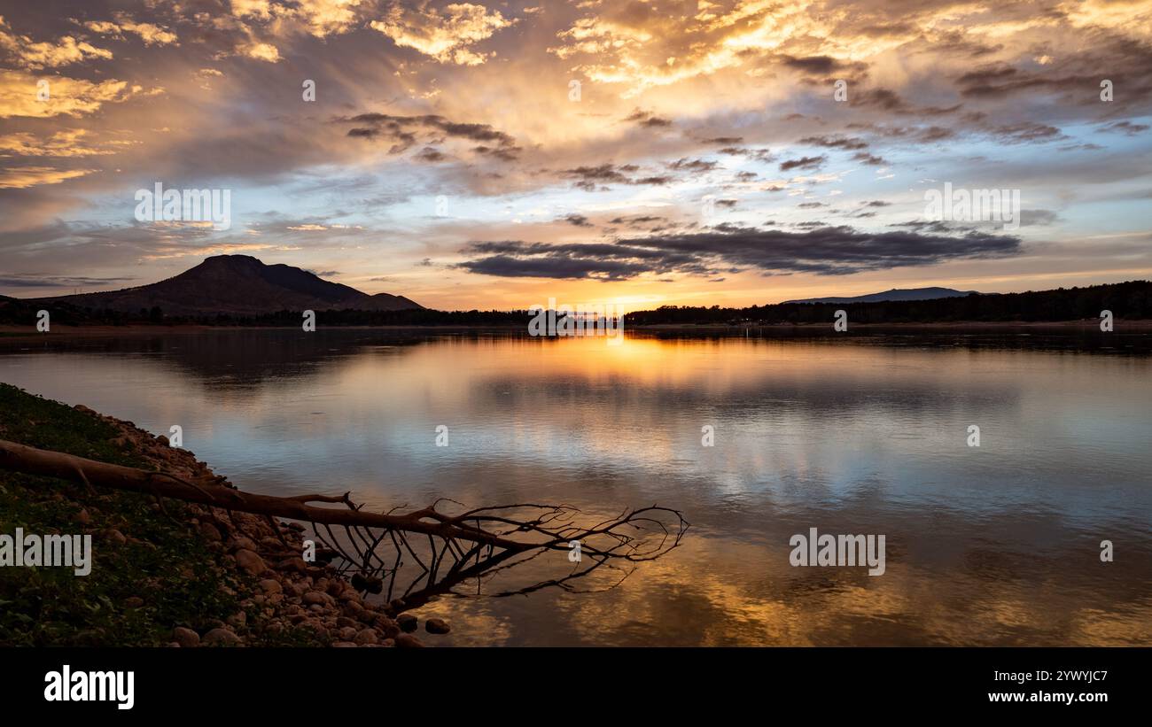 Paesaggio di un lago con il riflesso delle montagne e delle nuvole al tramonto autunnale a Granada (Spagna) Foto Stock