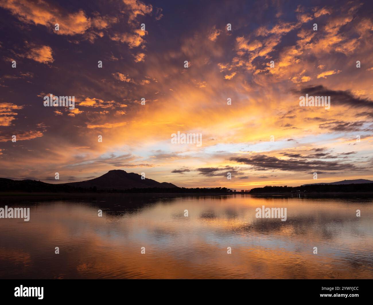 Paesaggio di un lago con il riflesso delle montagne e delle nuvole al tramonto autunnale a Granada (Spagna) Foto Stock