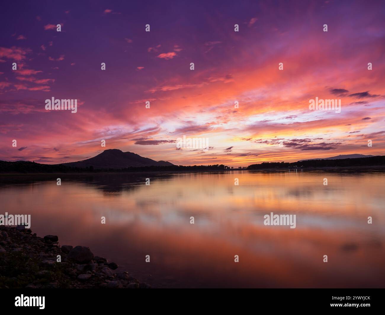 Paesaggio di un lago con il riflesso delle montagne e delle nuvole al tramonto autunnale a Granada (Spagna) Foto Stock