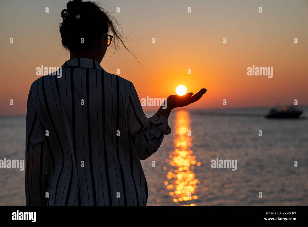 Donna che tiene Sunset sull'acqua Foto Stock